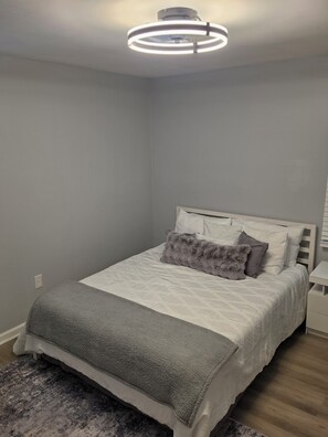 A bedroom with a bed, a bedside table, and a modern ceiling light fixture. - Modern Comfort 3-bedroom house near Downtown Atlanta (Atlanta)