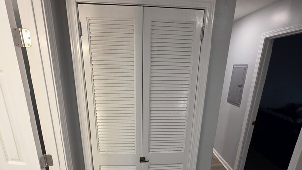 Ein Flur mit einer weißen Tür und einem Schrank mit Klappläden.