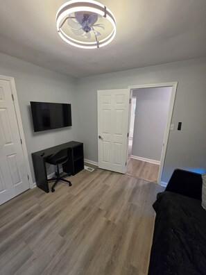 A room with a ceiling fan, a flat-screen TV mounted on the wall, a desk with a chair, and a bed. - Modern Comfort 3-bedroom house near Downtown Atlanta (Atlanta)