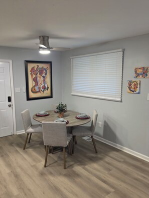 A dining area with a round table, four chairs, a ceiling fan, and artwork on the walls. - Modern Comfort 3-bedroom house near Downtown Atlanta (Atlanta)
