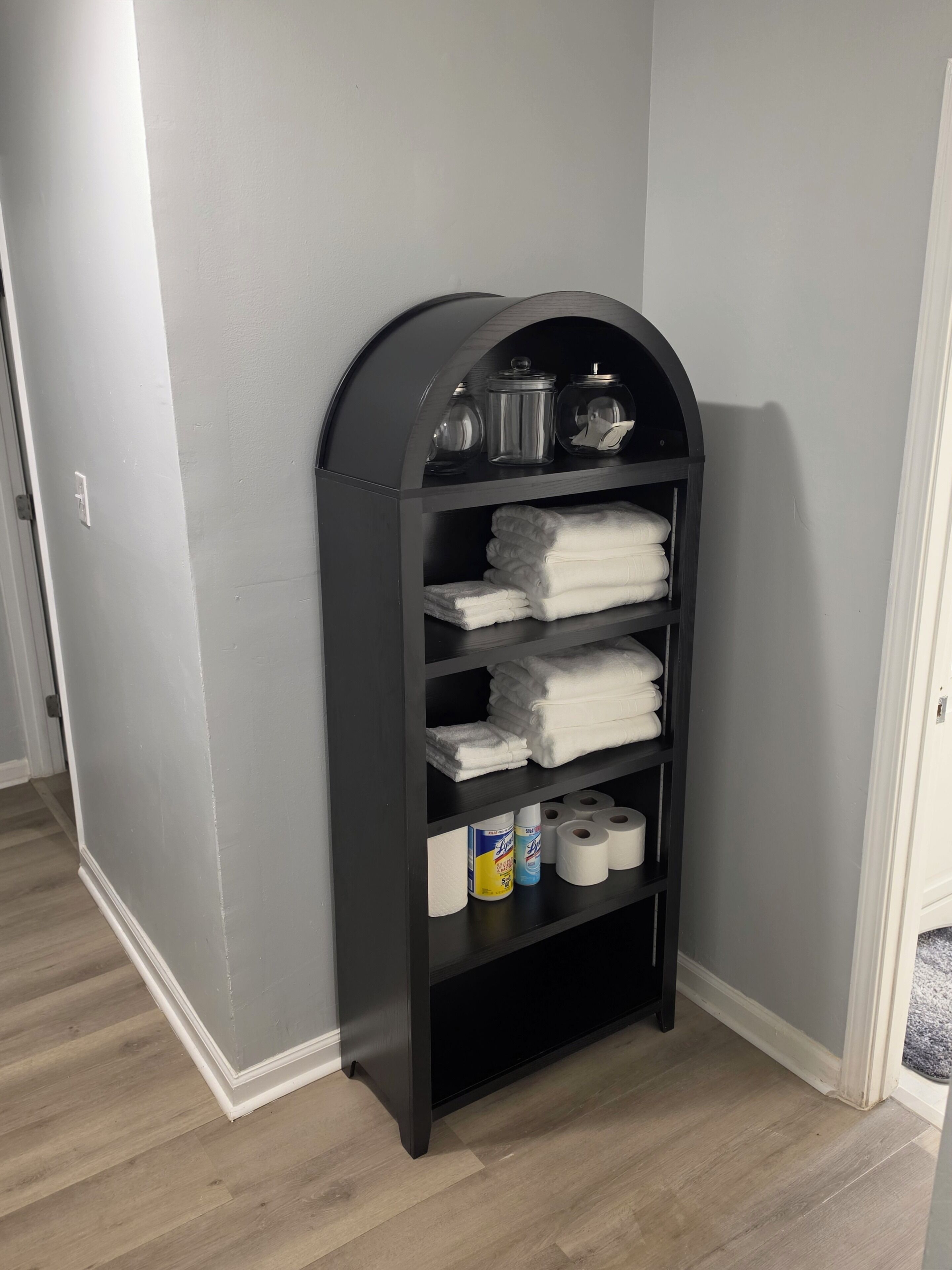 A black shelving unit with towels and toilet paper.