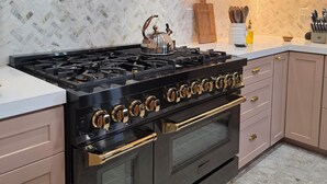 A kitchen with a black stove, white cabinets, and a herringbone patterned backsplash.