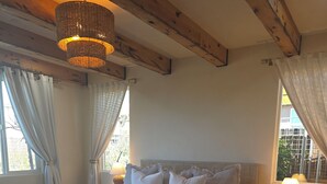 A bedroom with a bed, bedside lamps, a rug, and a wooden ceiling beam.