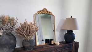 A wooden console table with a mirror, a lamp, and decorative items including dried plants and a vase.