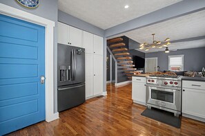 Eine moderne Küche mit einer blauen Tür, Edelstahlgeräten und einer Holztreppe.