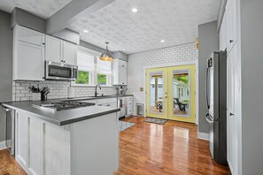 A modern kitchen with white cabinets, a stainless steel stove, and a large island. - Luxury Modern 30+ Day Bungalow. Walk Downtown. Hot Tub. Pet Friendly (Yellow Springs)