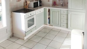 A kitchen with white cabinets, a microwave, a stove, and a ceiling fan. - T2 climatisé avec vue proche de Cannes et Grasse (Mouans-Sartoux)