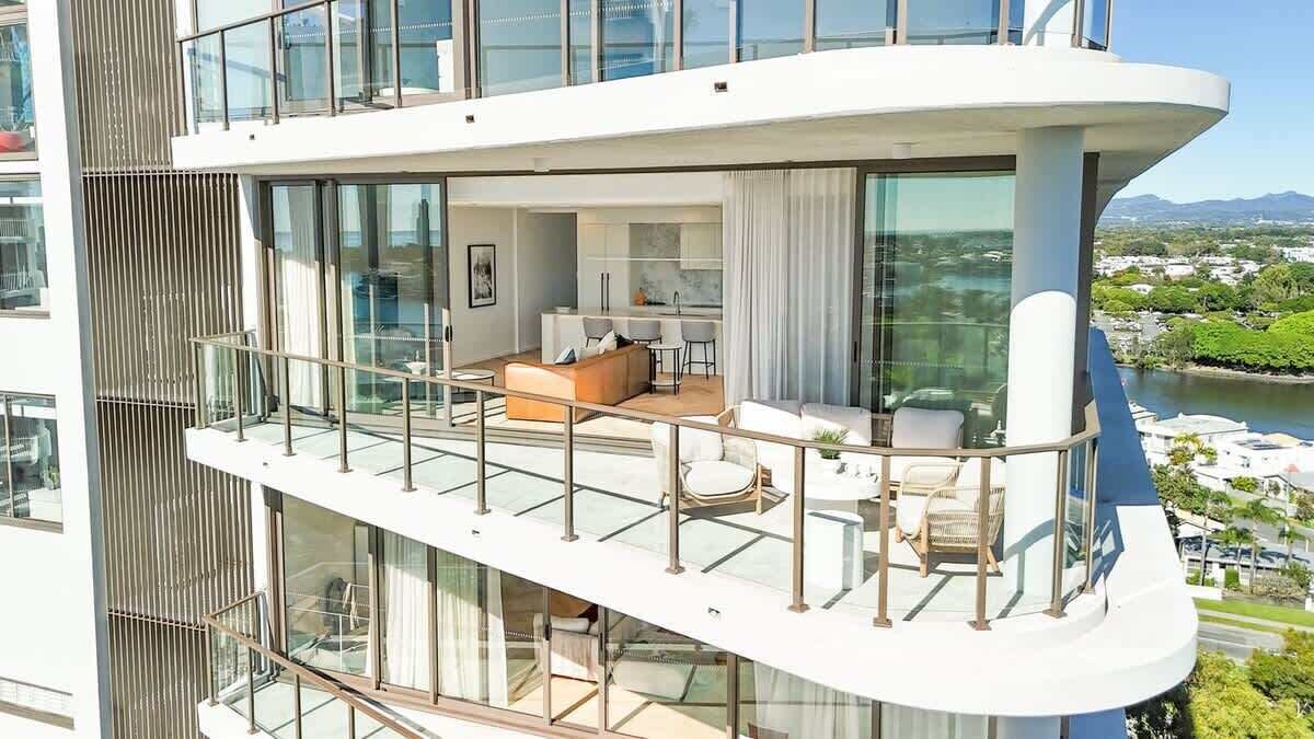 A modern multi-level residential building with a balcony, a dining area, and a view of a river.