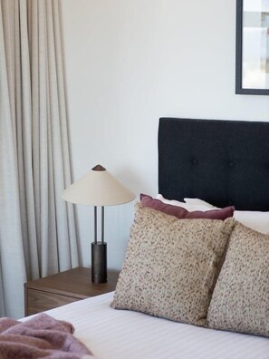 A neatly made bed with a headboard, a lamp, and a nightstand. - The Arches by Aryve | Surfers Paradise (Surfers Paradise)