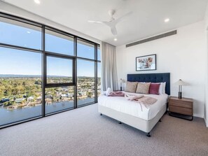 A bedroom with a large window, a bed, a bedside table, and a ceiling fan. - The Arches by Aryve | Surfers Paradise (Surfers Paradise)