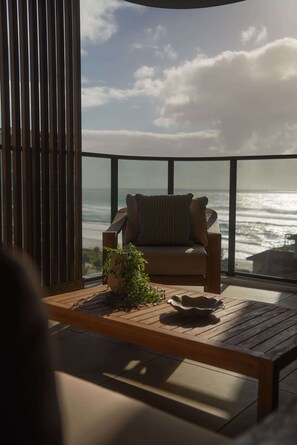A balcony with a wooden floor, a sofa, and a view of the ocean. - Sundays by Aryve | Ocean Terrace, Palm Beach (Palm Beach)