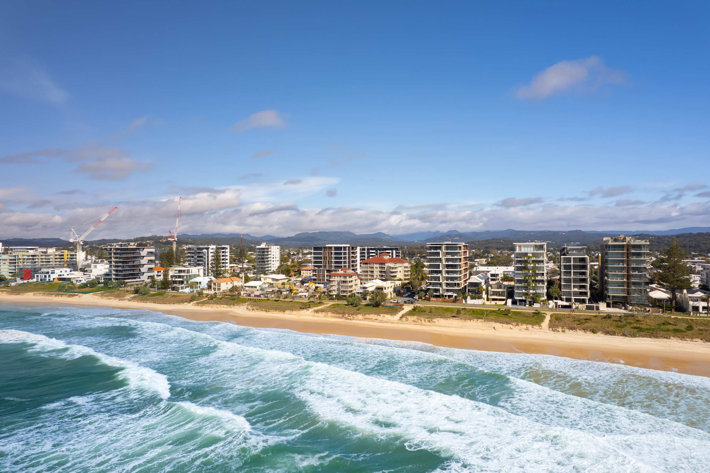Paisagem costeira urbana com uma orla marítima, edifícios altos e céu claro.