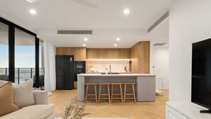 Uma cozinha moderna com ilha central, armários de madeira e uma grande janela com vista para uma varanda.