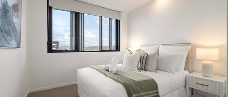Un dormitorio con cama, mesita de noche, lámpara, ventana y ventilador de techo.