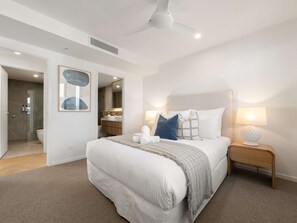 Une chambre à coucher moderne avec un grand lit, des lampes de chevet et un ventilateur de plafond.