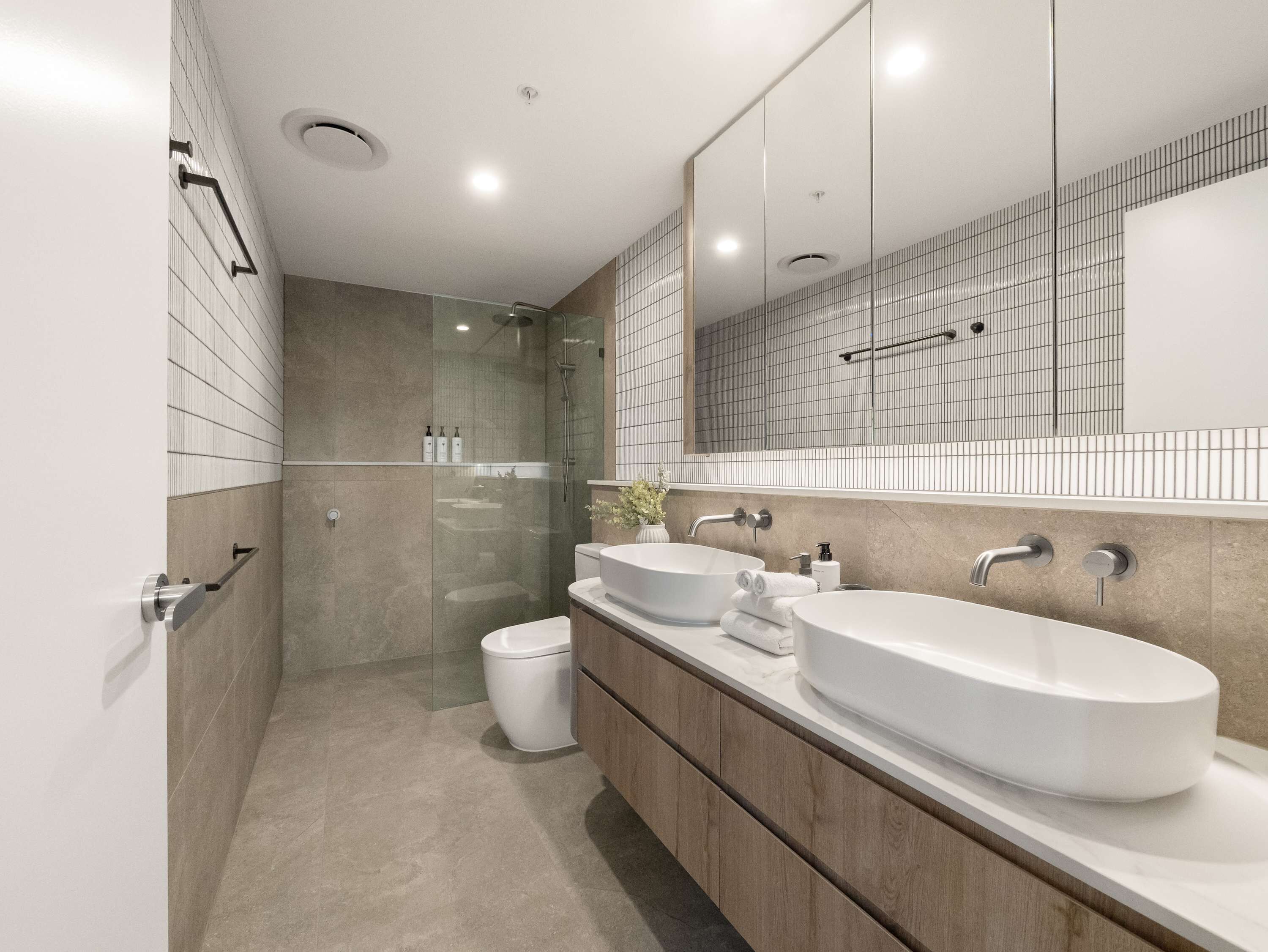 Un baño moderno con dos lavamanos, ducha y retrete.