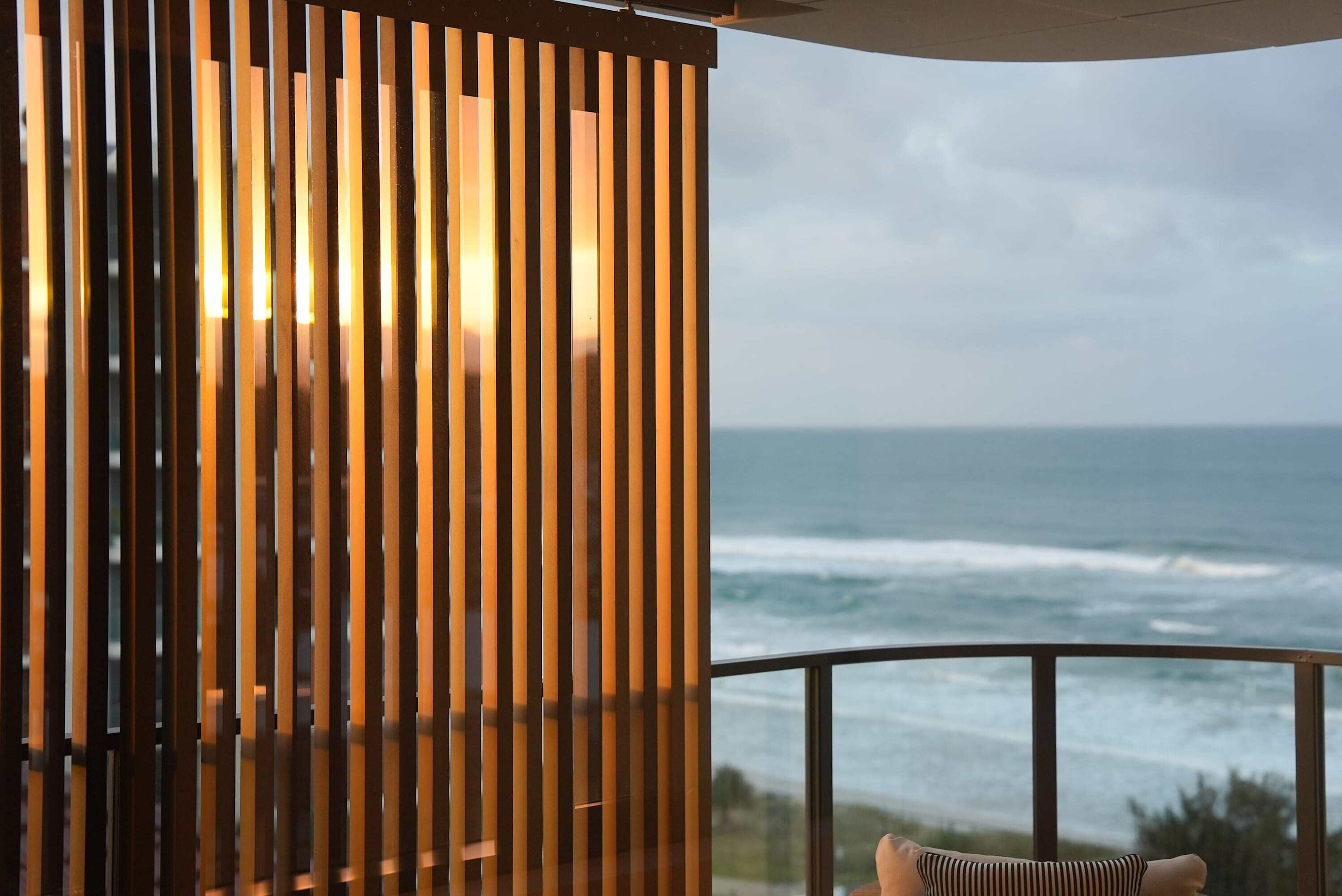 Ein Zimmer mit Meerblick, ausgestattet mit einer Holzhakepartition und einem Balkon mit Geländer.