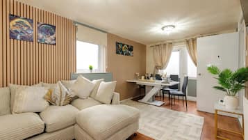 A modern living room with a sectional sofa, a dining table, and a potted plant.