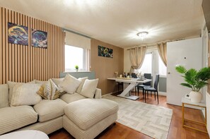 Una sala moderna con un sofá modular, una mesa de comedor y una planta en maceta.