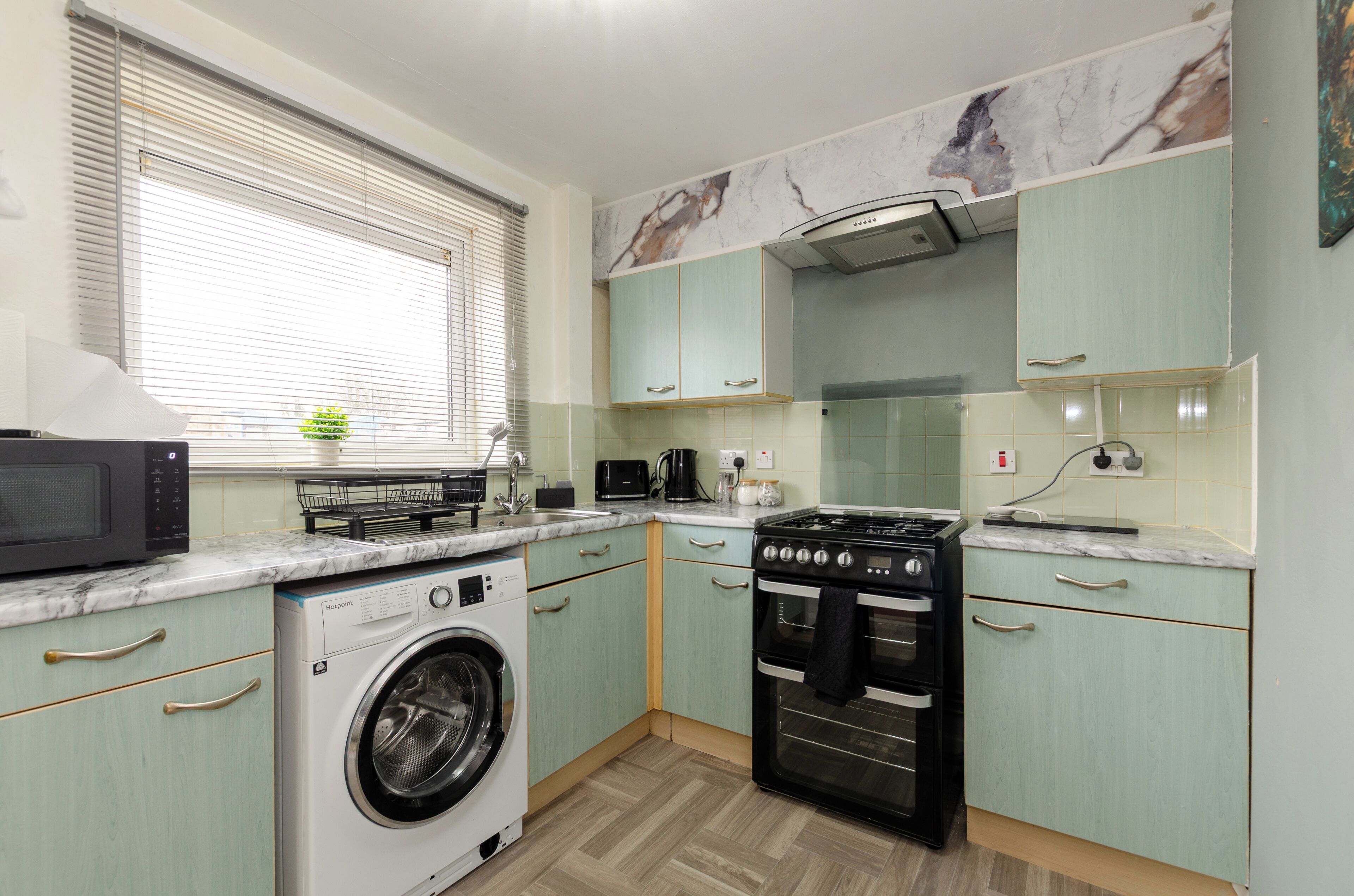 A compact kitchen with a washing machine, microwave, stove, and oven.