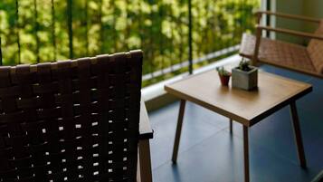 Een balkon met uitzicht op groene heuvels, een stoel, een tafel en een kleine plant.