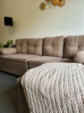 A beige sofa with a textured throw blanket in a living room.
