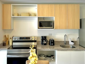 A modern kitchen with stainless steel appliances, a microwave, a coffee maker, and a sink.