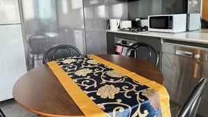 Ett modernt kök med vitvaror i rostfritt stål, ett matbord med en dekorativ löpare och en diskmaskin från Bosch.