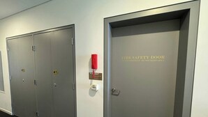 En hall med två grå dörrar, varav den ena är märkt som en brandskyddsdörr och har en röd nödtelefon samt en skylt som visar utgångsnivå 7.