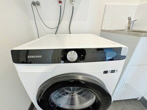 Eine Samsung Waschmaschine mit Frontlader in einer modernen Küche, inklusive eingebautem Spülbecken und Arbeitsplatte.