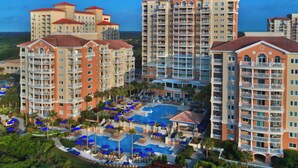 Resort com vários edifícios altos, uma piscina central e áreas de estar ao ar livre.