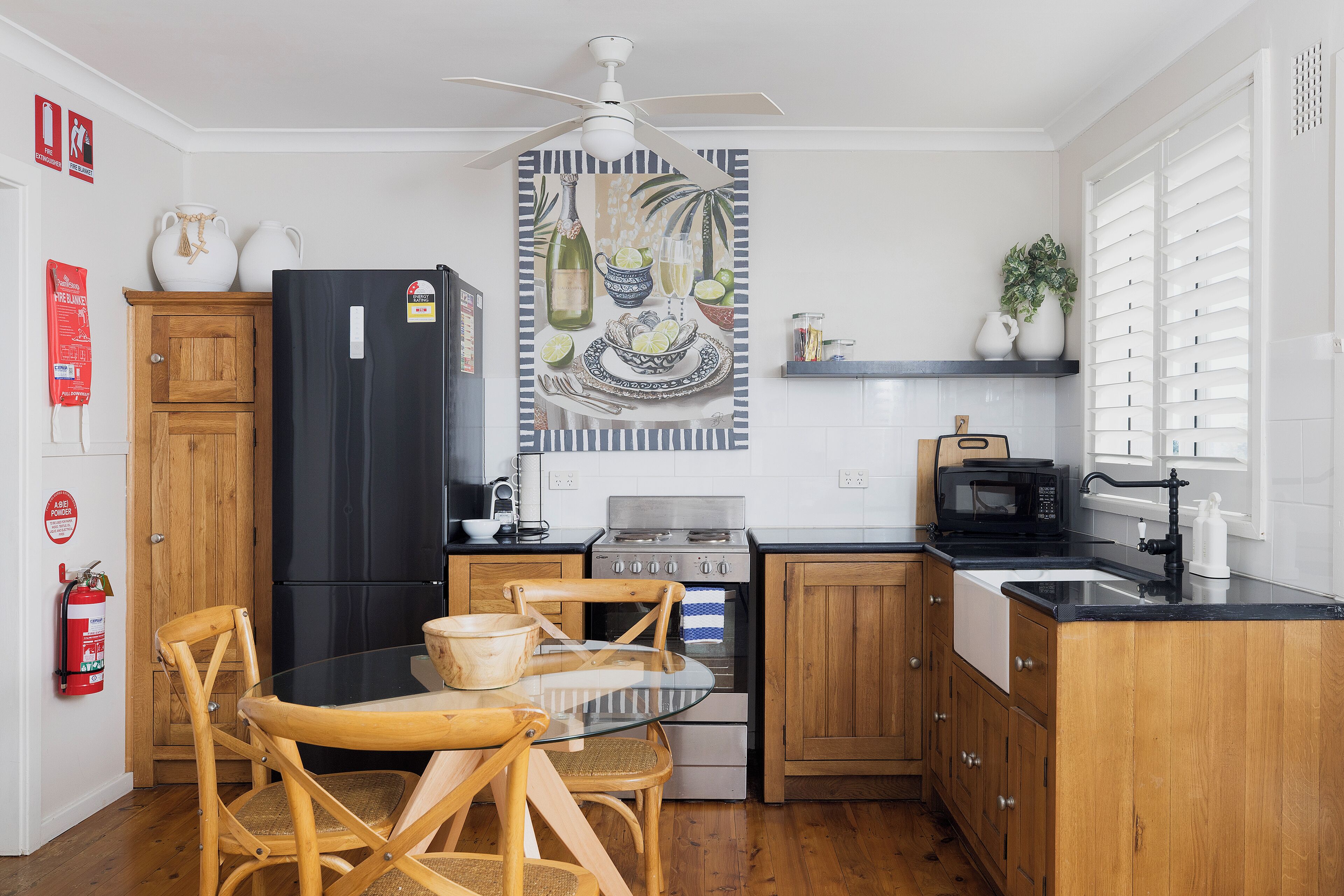 A compact kitchen with a dining area, wooden cabinets, a black refrigerator, a microwave, and a gas stove.