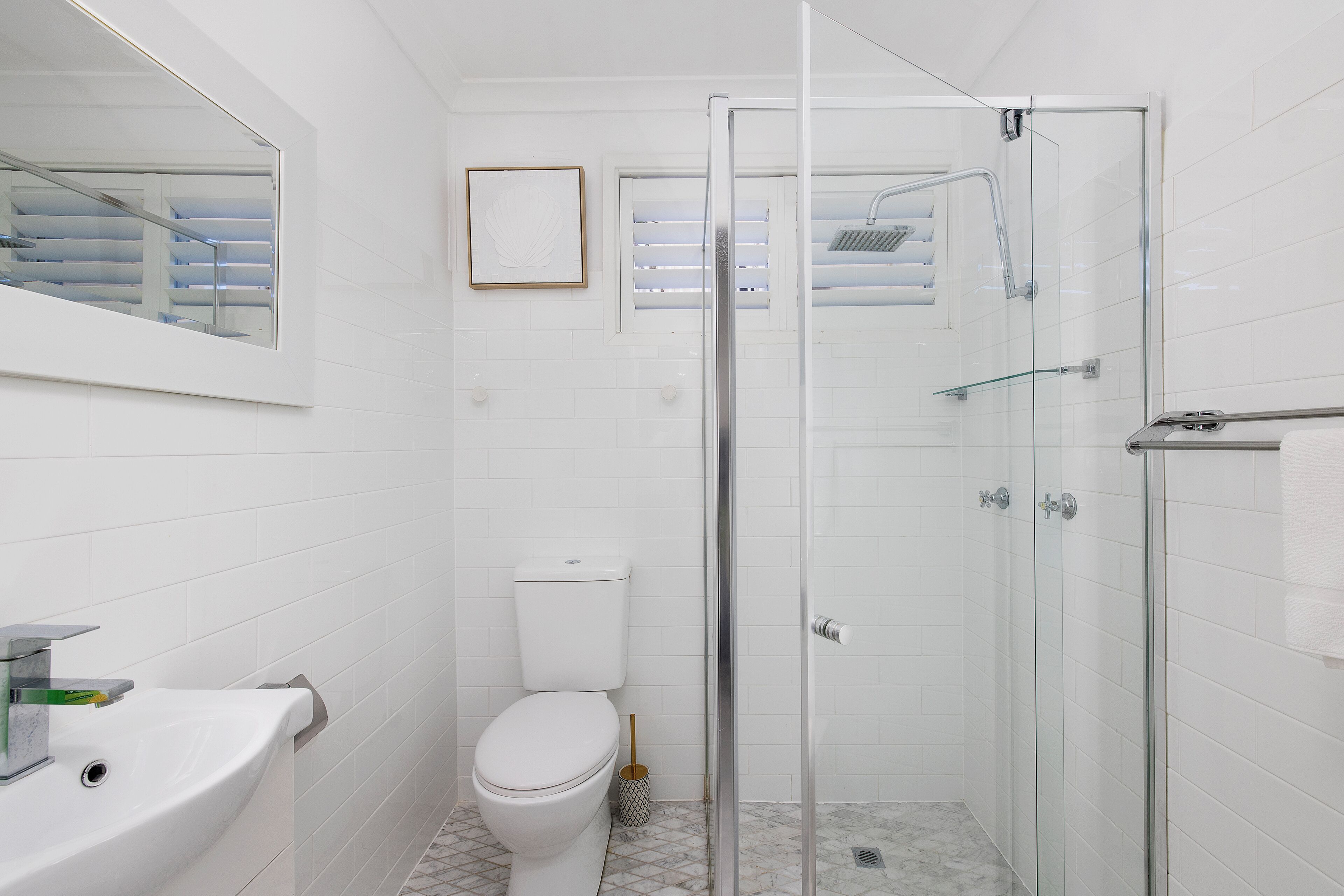 Une salle de bain comprenant des toilettes, un lavabo et une cabine de douche fermée par des parois en verre.