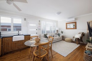 A modern kitchen with a dining table, wooden chairs, and a built-in oven. - Berrigal 4 Beachfront (Shoal Bay)