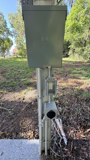 An outdoor electrical box with a metal structure, surrounded by grass and trees. - Capo's Cast Aways Lake House (Haines City)