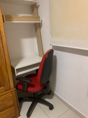 A corner workspace with a red office chair, white shelving, and a wooden cabinet. - Olympic Bar well located (Rio de Janeiro)