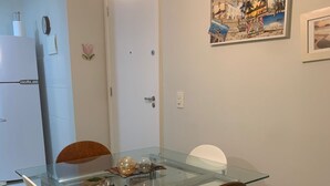 Ein Essbereich mit einem Glastisch, weißen Stühlen und einem weißen Schrank.