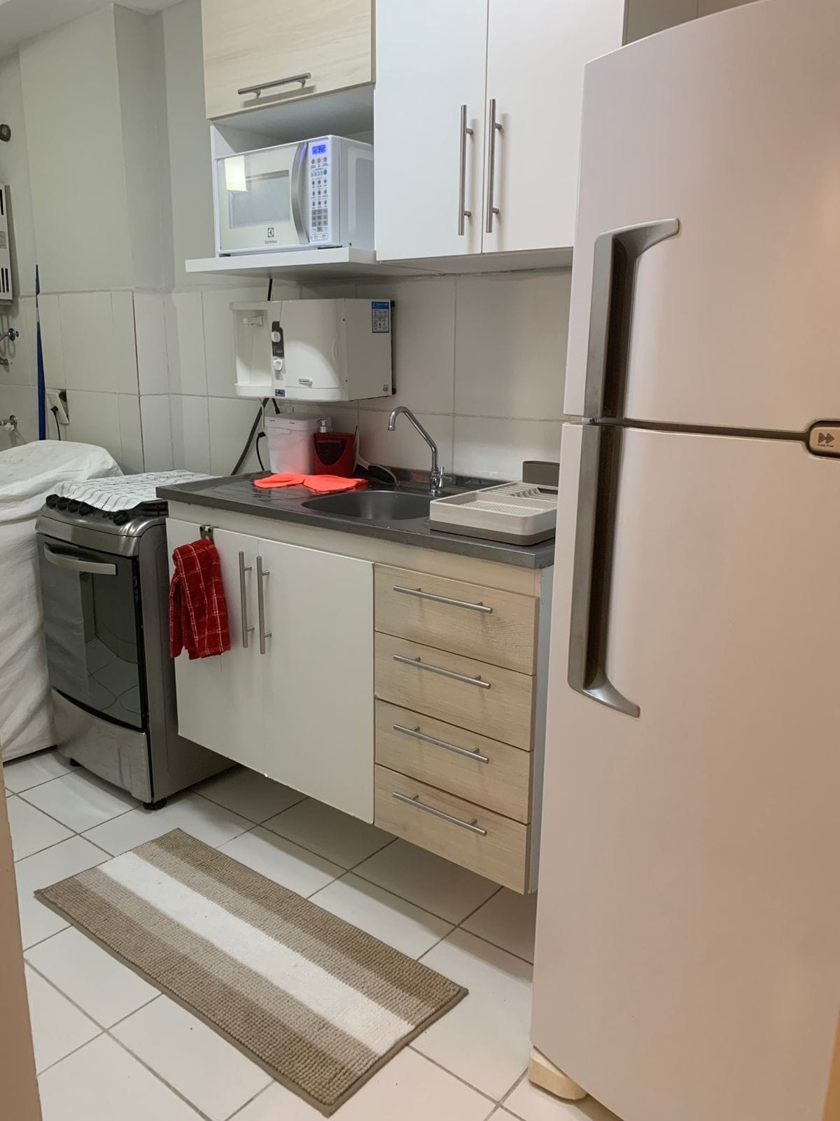 Een keuken met witte kastjes, een roestvrijstalen koelkast, een magnetron en een fornuis.