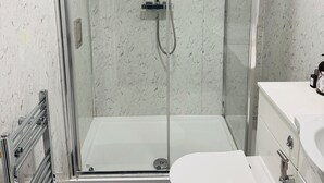 A modern bathroom with a glass shower enclosure, a white toilet, and a white sink.