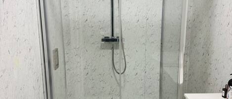 A modern bathroom with a glass shower enclosure, a white toilet, and a white sink.