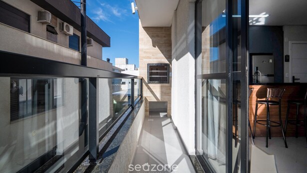 Un moderno edificio residencial con balcón, zona de cocina y comedor con taburetes de bar.
