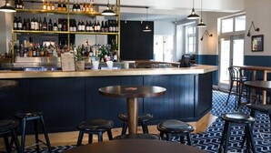 A bar area with a counter, stools, and shelves of bottles. - Blues Point Hotel (McMahons Point)