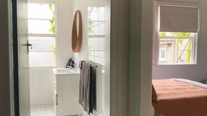 A bathroom with a white sink, mirror, and towel rack. - Blues Point Hotel (McMahons Point)