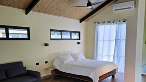 Een slaapkamer met een houten plafond, een bed, een bank en een raam.