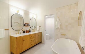 Ein modernes Badezimmer mit einer freistehenden Badewanne, einem Holzwaschtisch, zwei Spiegeln und einer Duschkabine.