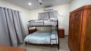 A bunk bed room with a wooden wardrobe, a bedside table, and a curtain. - Cozy 3-bedroom house with AC in charming, centrally located Masatepe, (Masatepe)