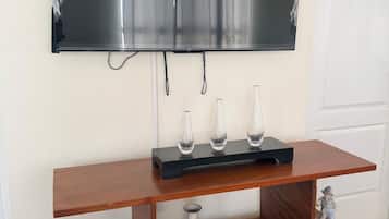 Un téléviseur à écran plat fixé au mur, au-dessus d’un meuble télé en bois agrémenté d’objets décoratifs.