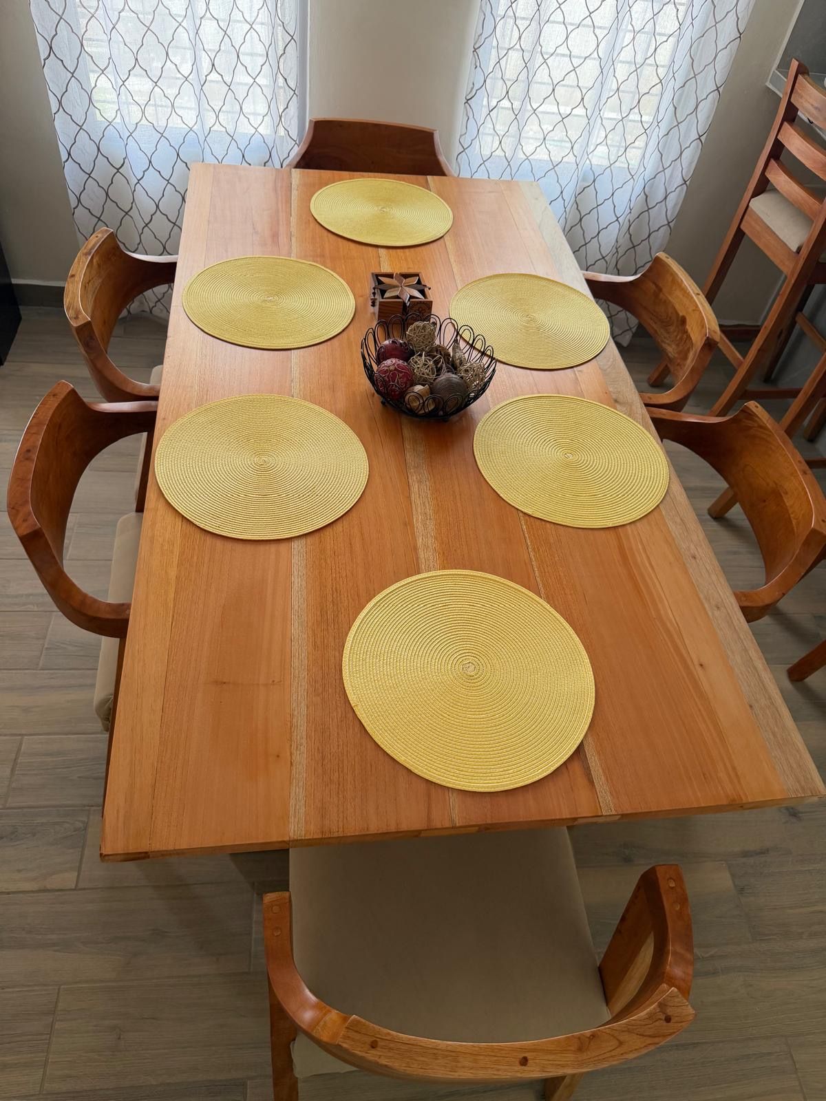 Un tavolo da pranzo in legno con sei sottopiatti rotondi e un elemento decorativo al centro.