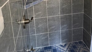 A shower area with a tiled wall, a handheld showerhead, a wall-mounted faucet, and a shelf with toiletries. - Cozy 3-bedroom house with AC in charming, centrally located Masatepe, (Masatepe)