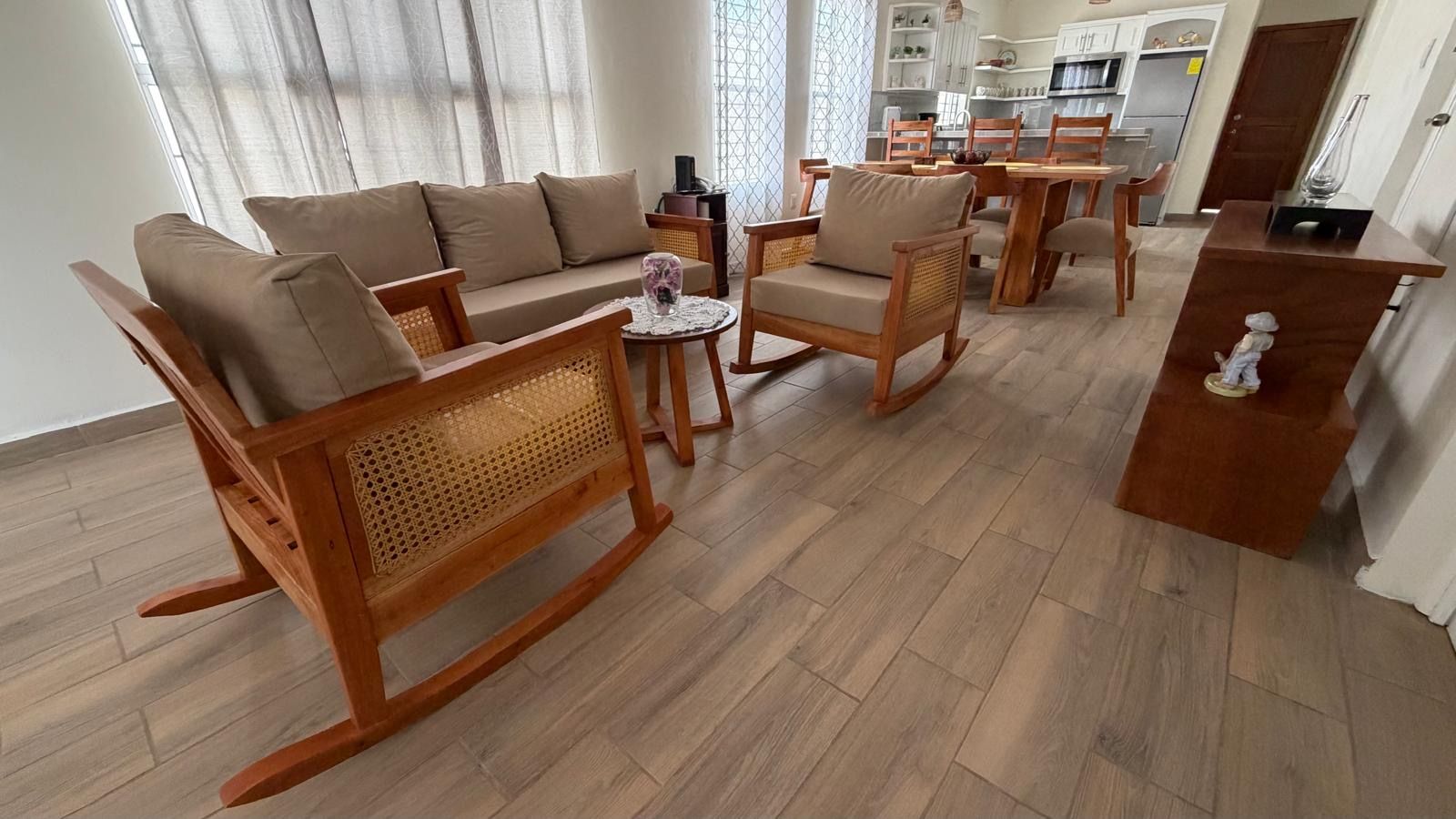 Una sala de estar con sofá, sillas, una mesa de centro y un comedor con mesa y sillas.